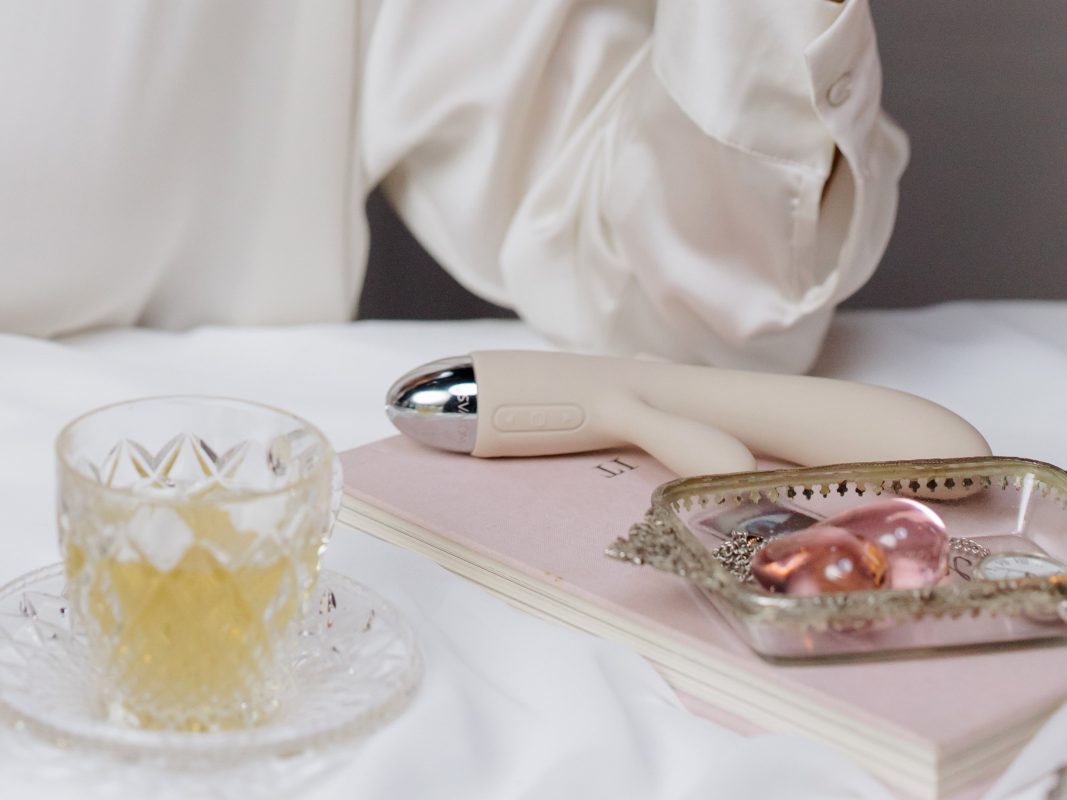 Geklede vrouw met seksspeeltje op bed